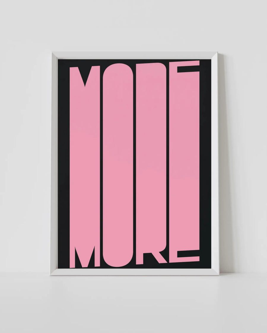 Framed typography art print with pink 'MORE' on black background, white frame