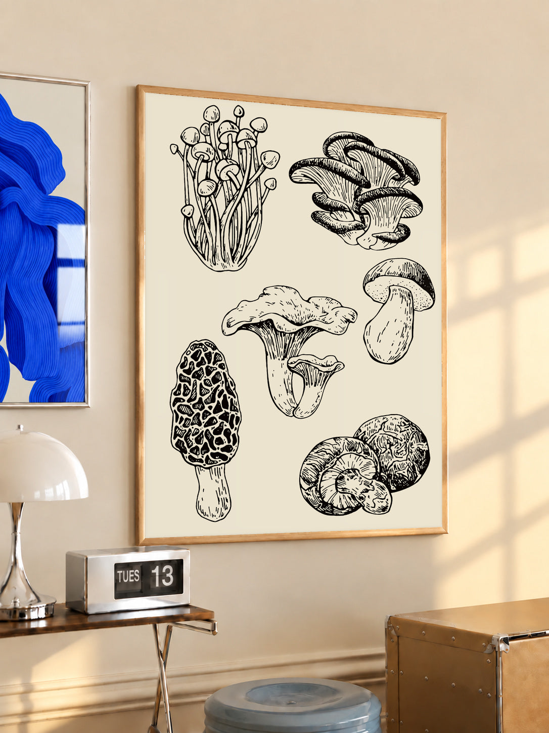 Six mushroom specimen studies with varied caps stems and gills in black ink style in an oak frame above a console beside a blue print and calendar