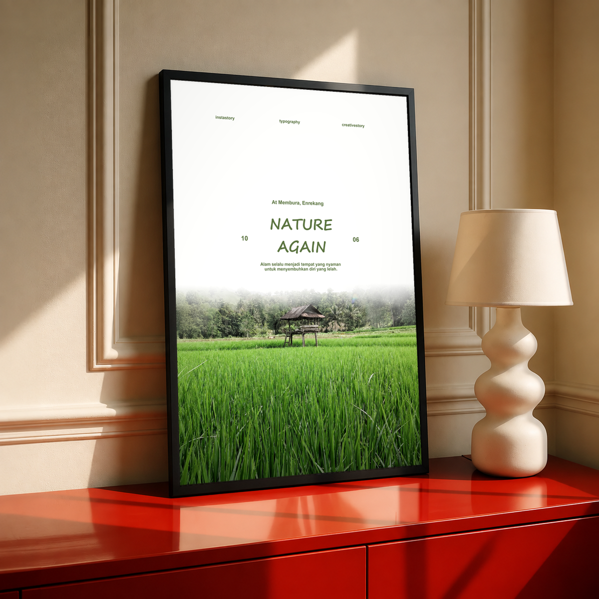 Green rice field and small wooden pavilion beneath Nature Again lettering; black framed print on a red cabinet