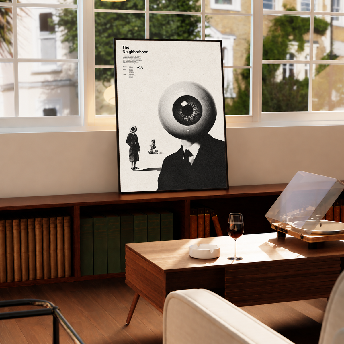 A suited eyeball-headed figure with smaller surreal figures on cream in a black frame by a bright window above a record player