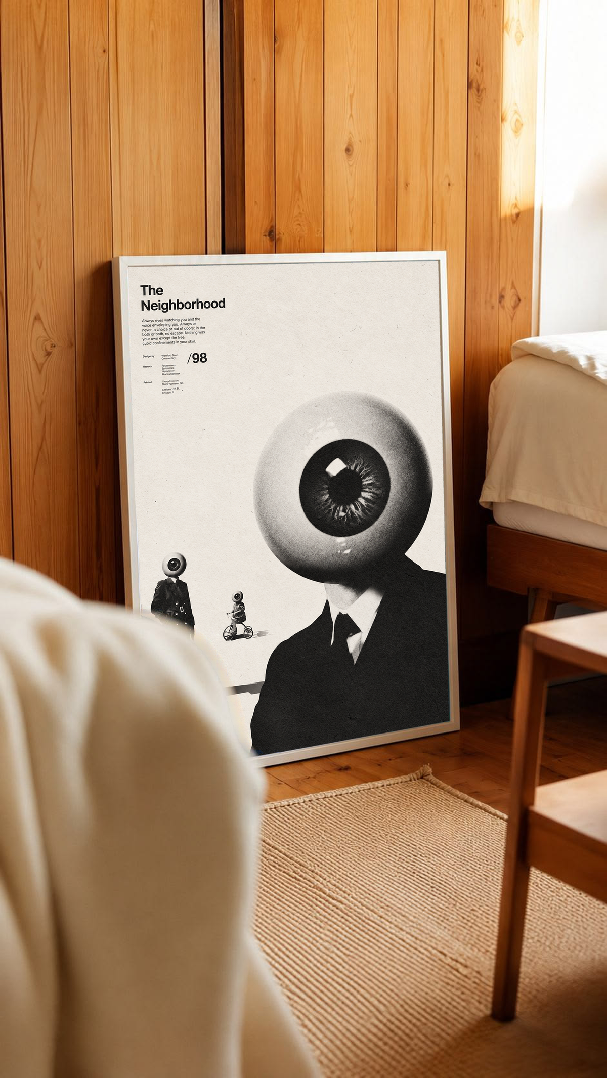 A suited eyeball-headed figure with smaller surreal figures on cream in a white frame leaning against warm wooden wall panels