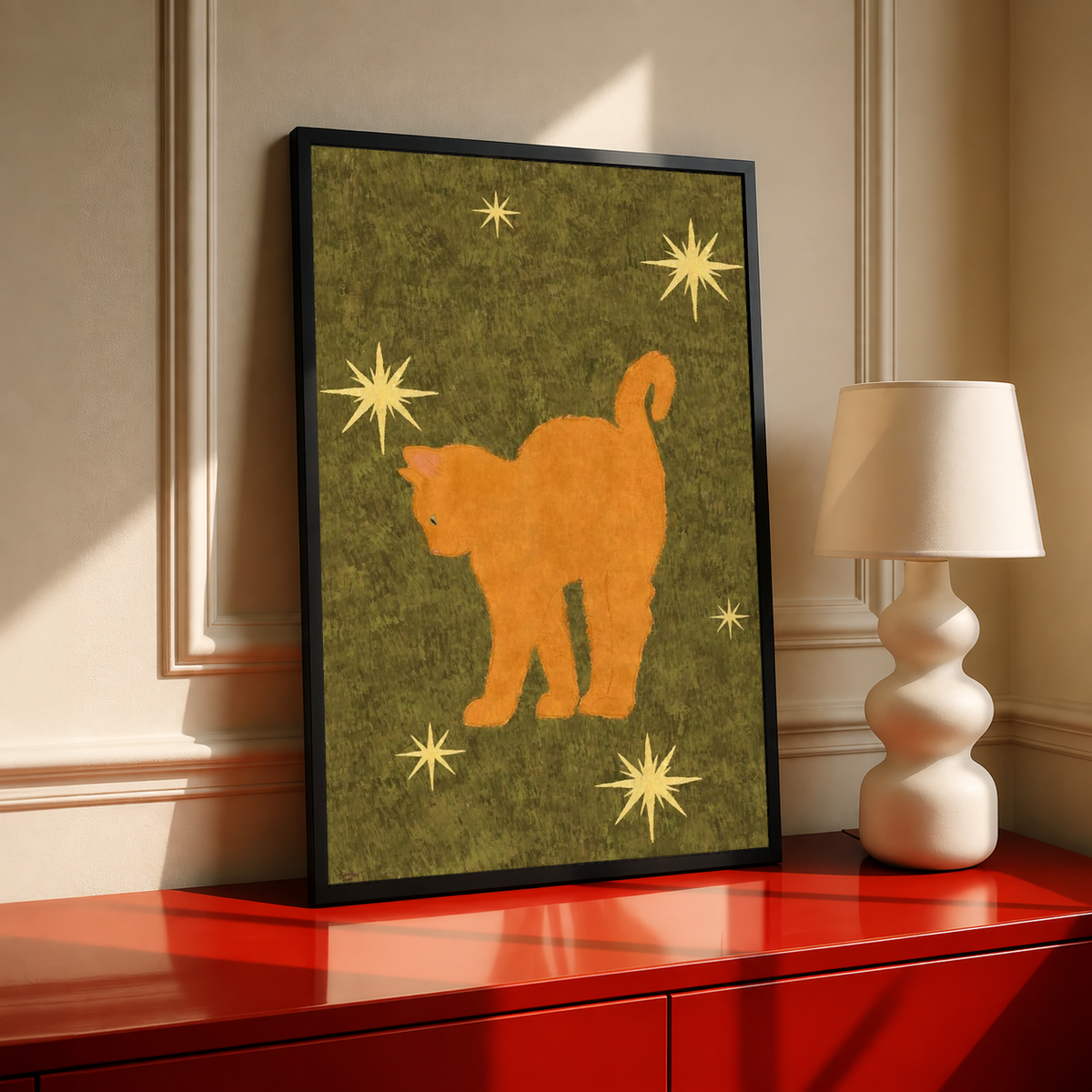 Orange cat art print with gold stars on olive green, framed in black