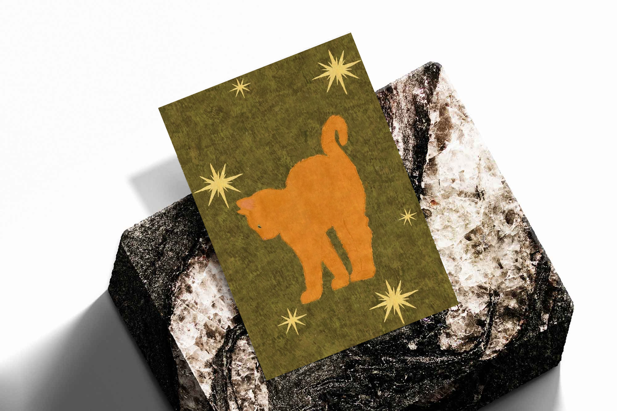 Orange cat and star art print on olive green, placed on dark textured surface