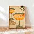 Framed orange cocktail still life wall art showing two martini glasses on green stems