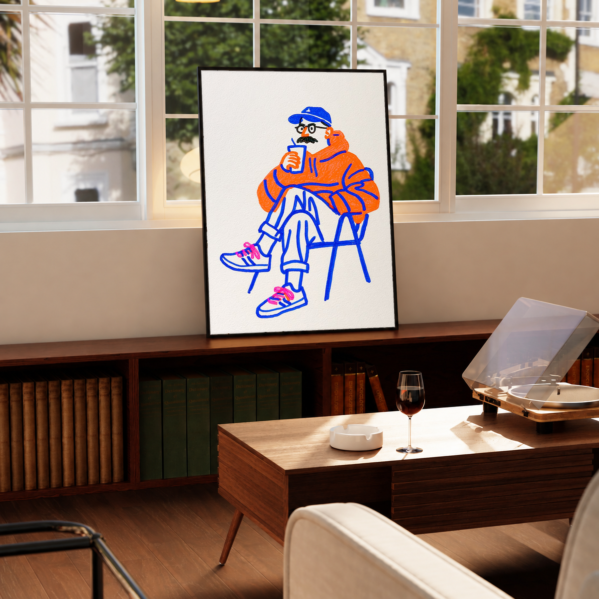 Coffee art print in black frame, seated orange figure with blue linework
