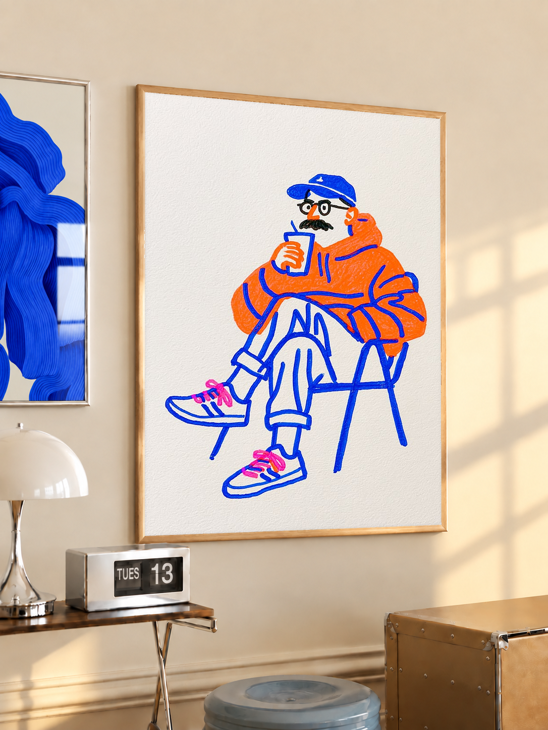 Framed coffee art print with seated orange character and blue linework
