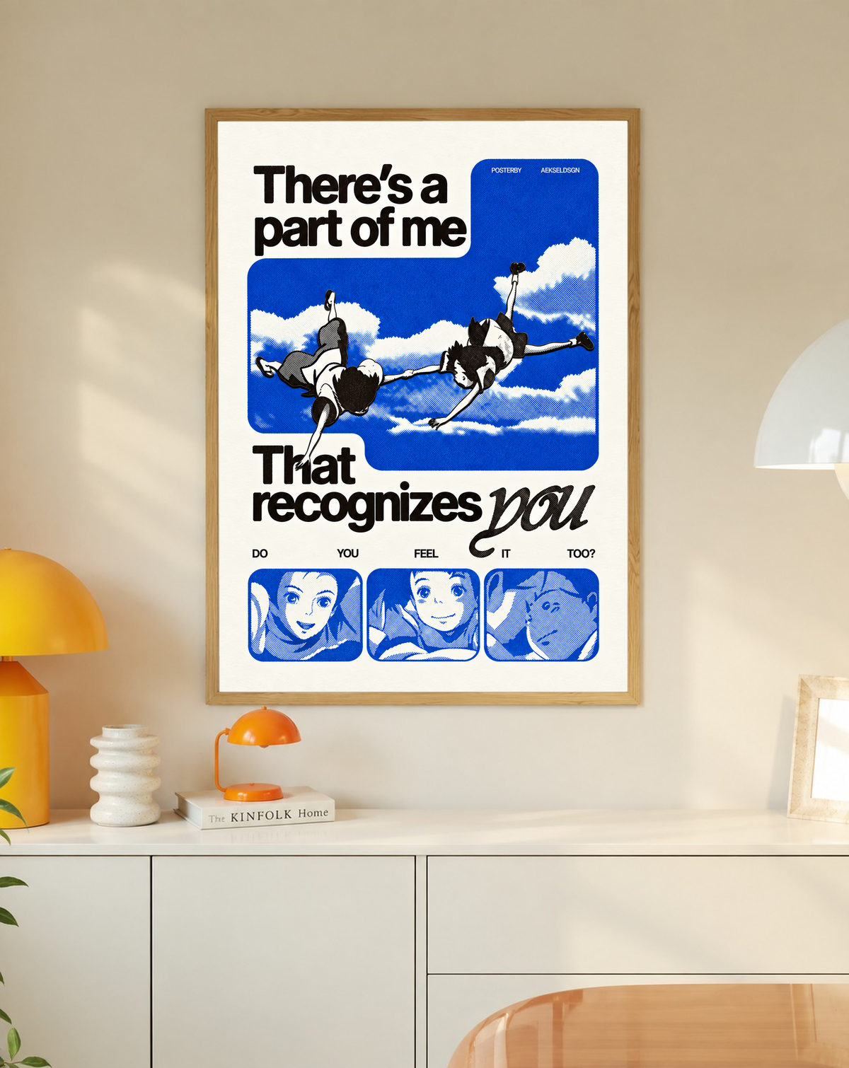 Two anime figures against blue sky with character portraits and a romantic recognition quote in a slim oak frame on a cream wall above a white cabinet