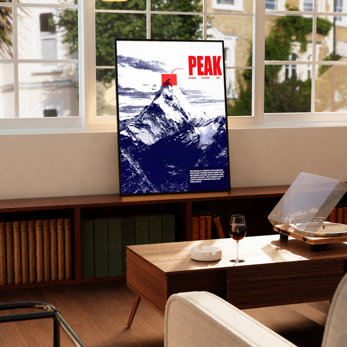 White and navy halftone Ama Dablam mountain with red PEAK lettering; framed print beside a window