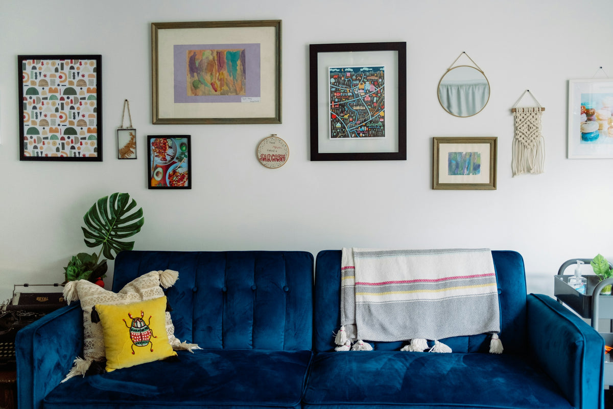Gallery wall with framed artwork above a blue sofa. Photograph by Taylor Heery.