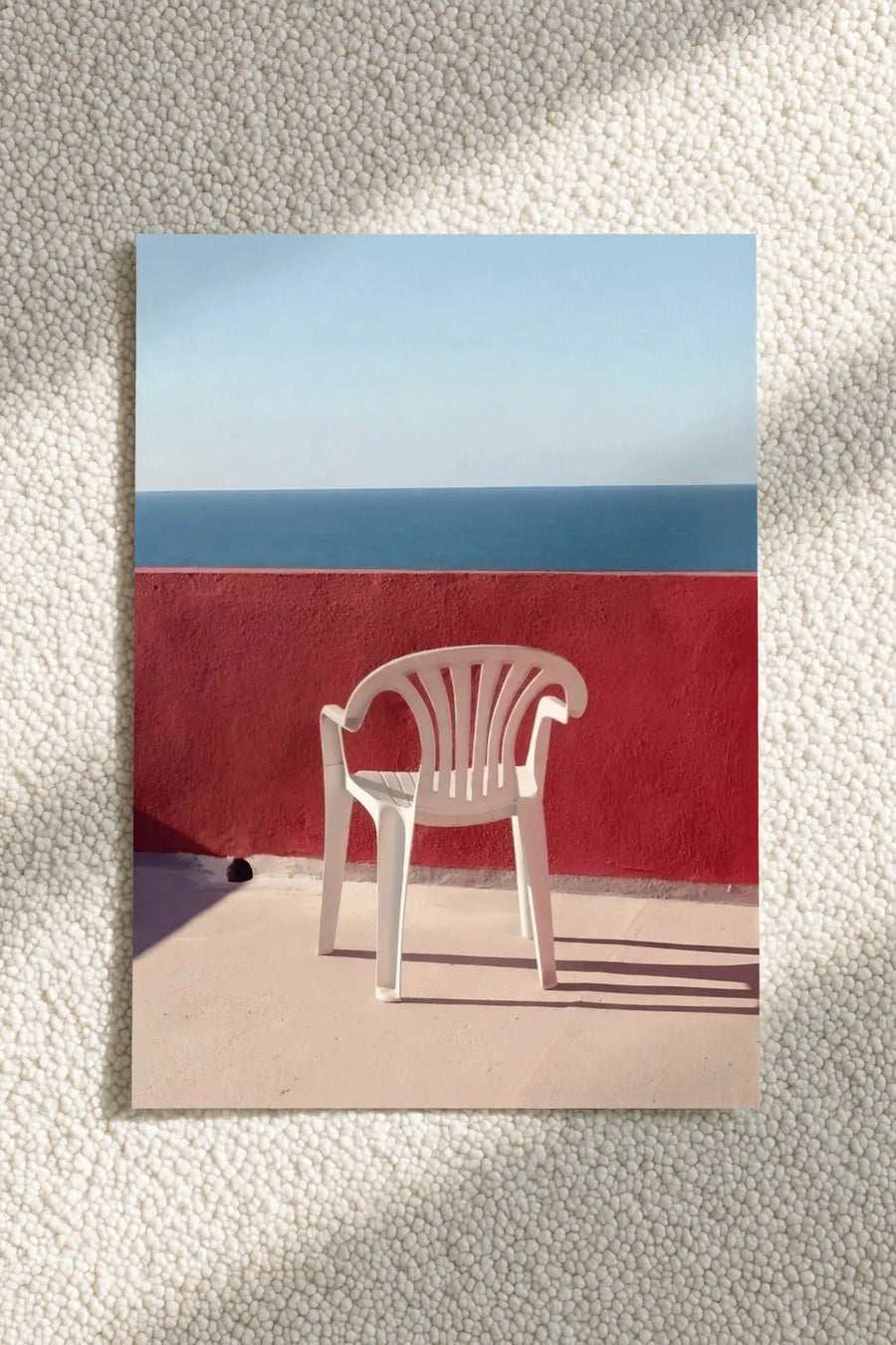 Beach chair wall print with white empty chair in front of red wall and blue horizon