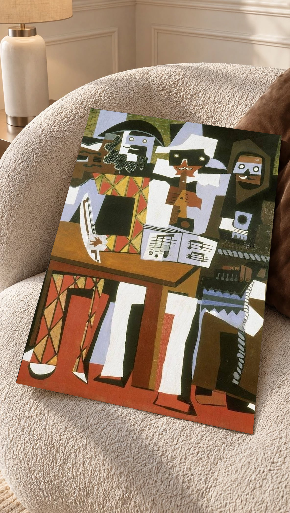 Picasso Three Musicians with angular masked figures, red diamonds and an accordion as an unframed print resting on a boucle chair