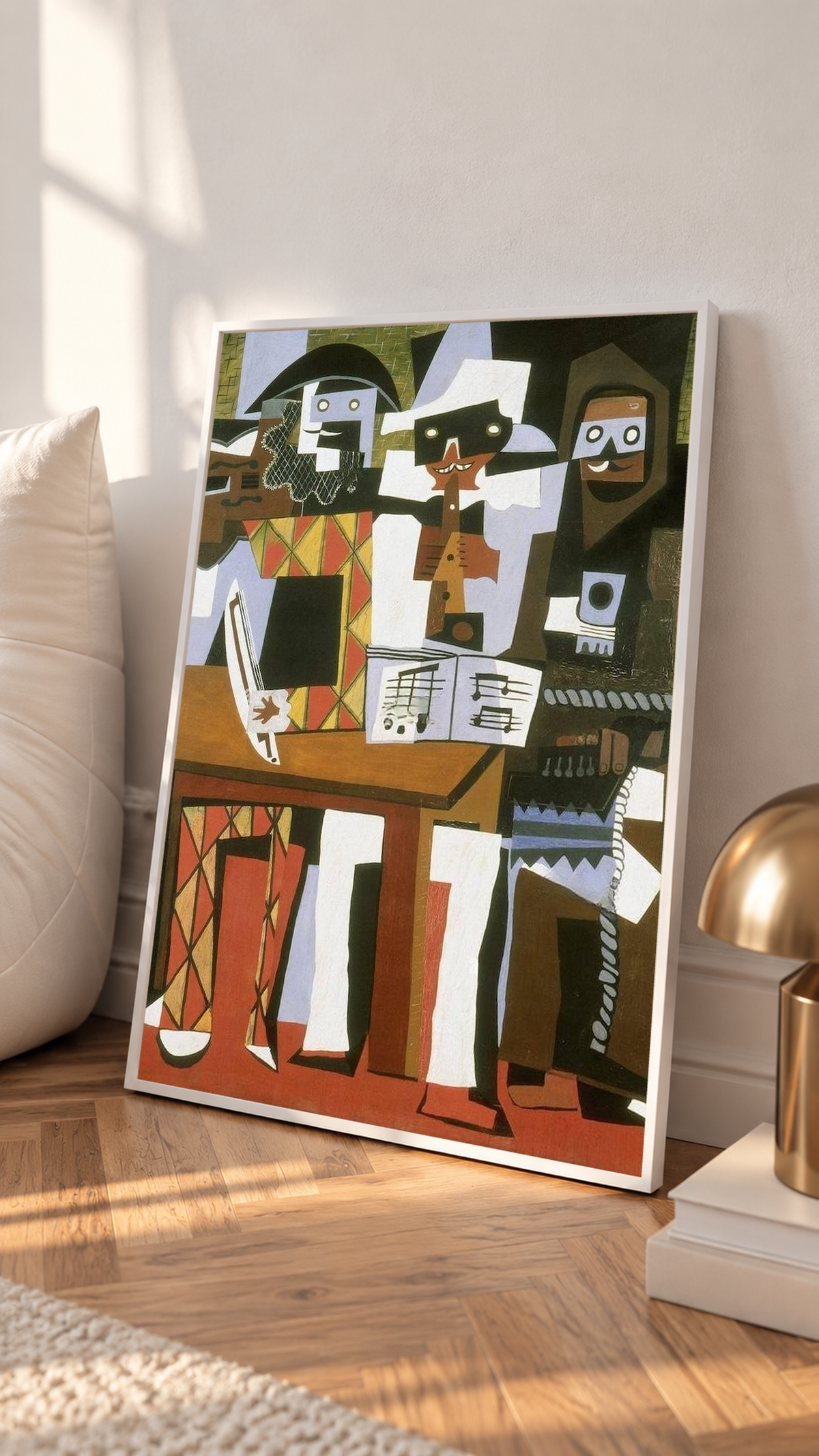 Picasso Three Musicians with angular masked figures, red diamonds and an accordion in a white frame leaning on a sunlit floor beside a brass lamp