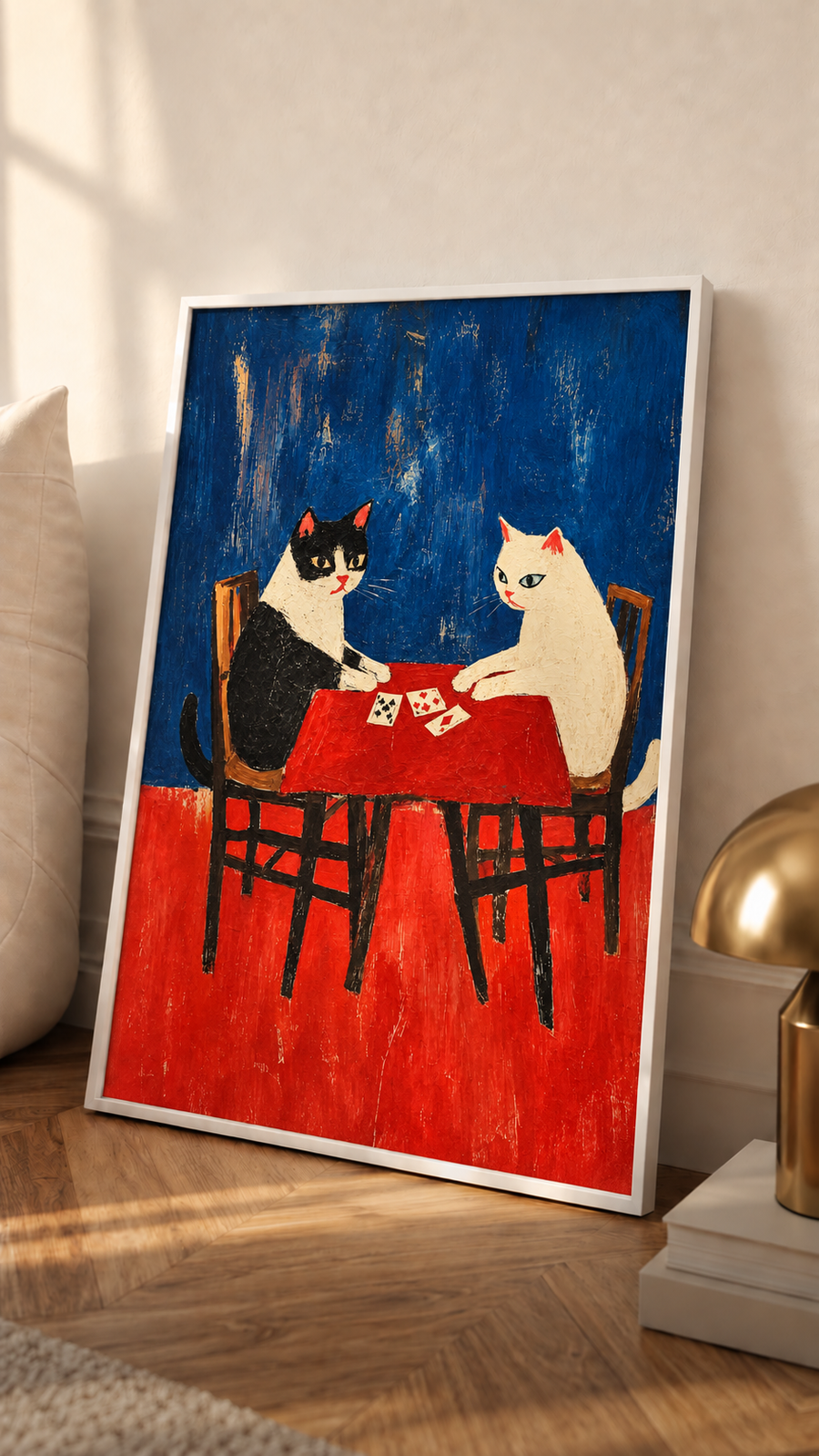 White-framed folk art wall art of cats playing cards at a red table