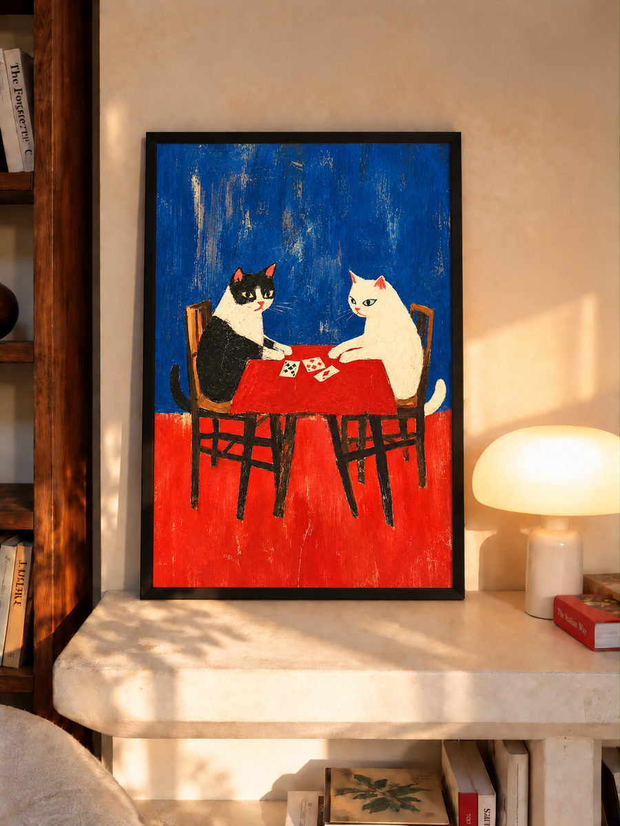 Dark-framed folk art wall art of two cats playing cards on red table