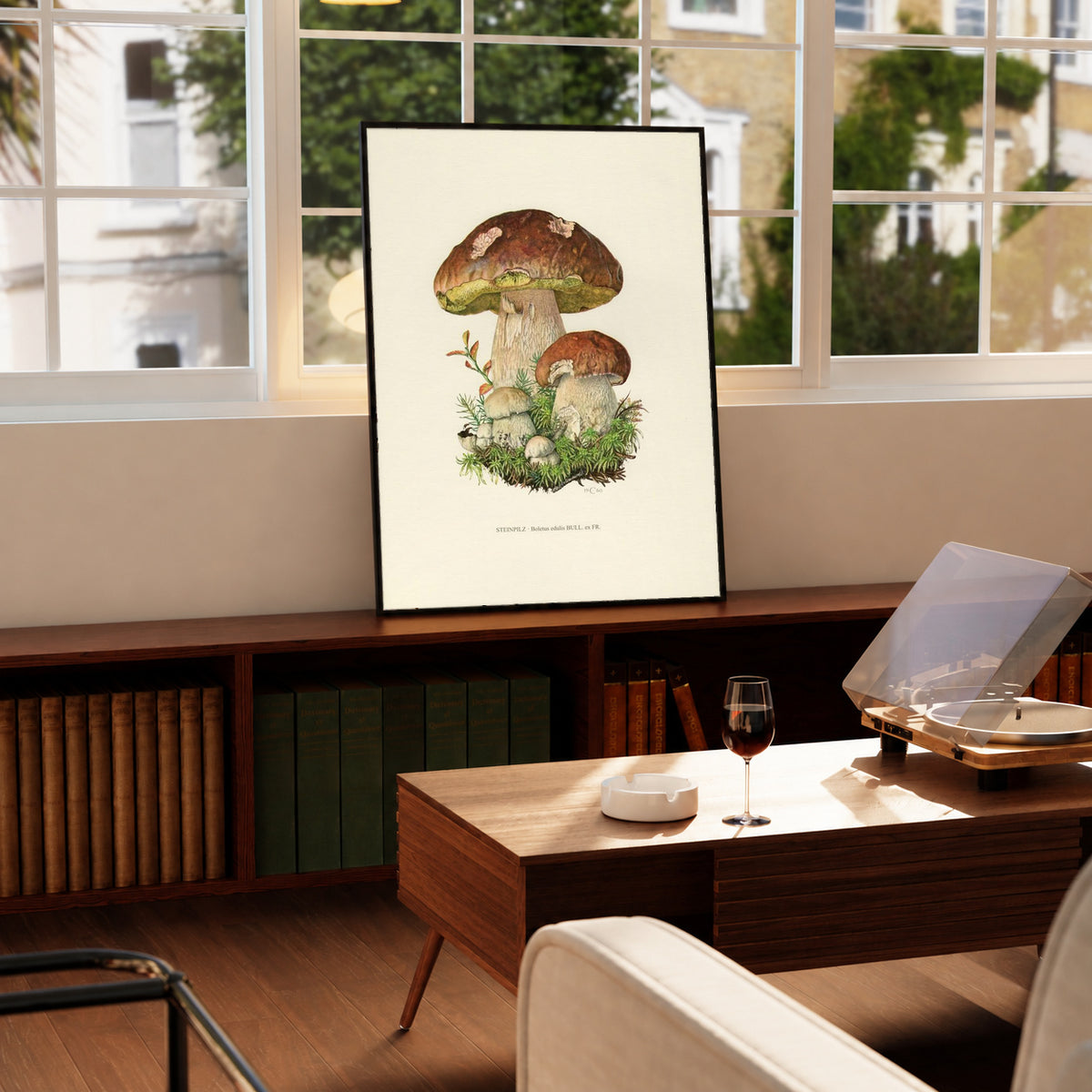 Brown porcini mushrooms with moss and a printed Steinpilz Boletus edulis caption in a black frame on a wooden cabinet beside a window and record player