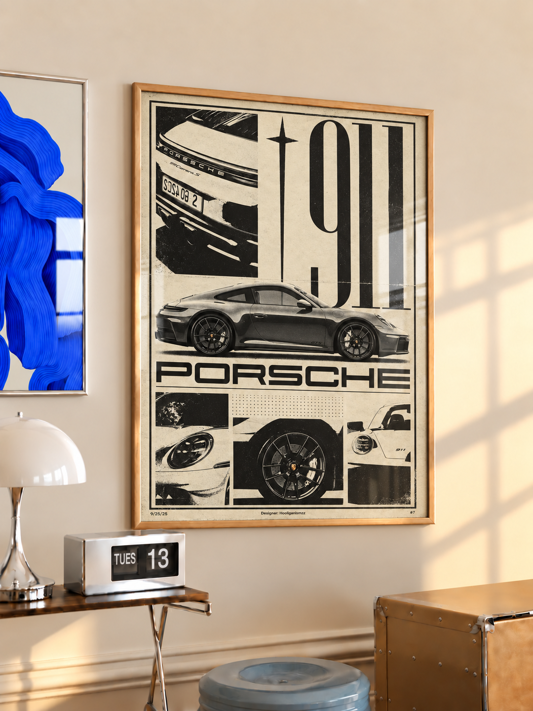 Wood-framed black-and-white Porsche 911 collage hanging above a wooden side table with a white lamp.