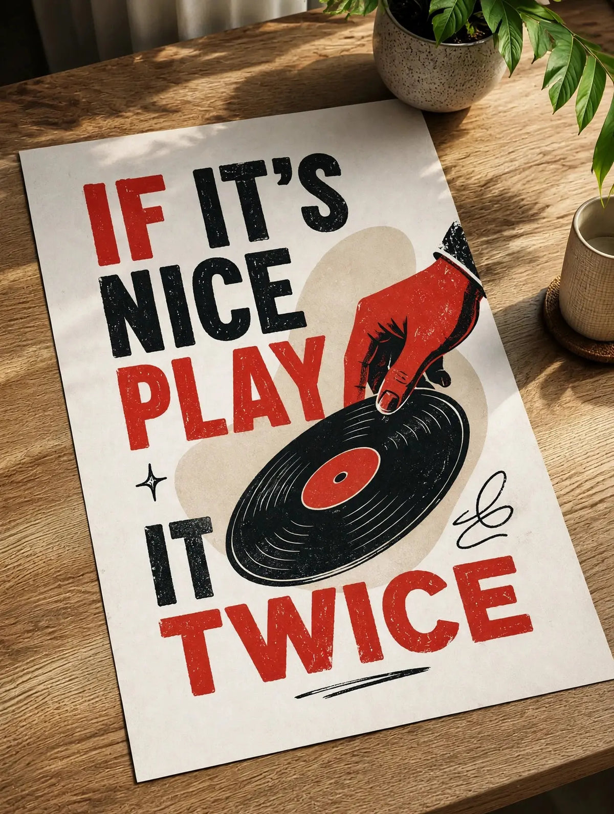 Vinyl record wall art poster on tabletop with red and black “If It’s Nice Play It Twice” text