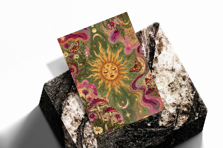 Celestial sun face, flowers and mushrooms as an unframed print propped against a pale wall on a rough stone