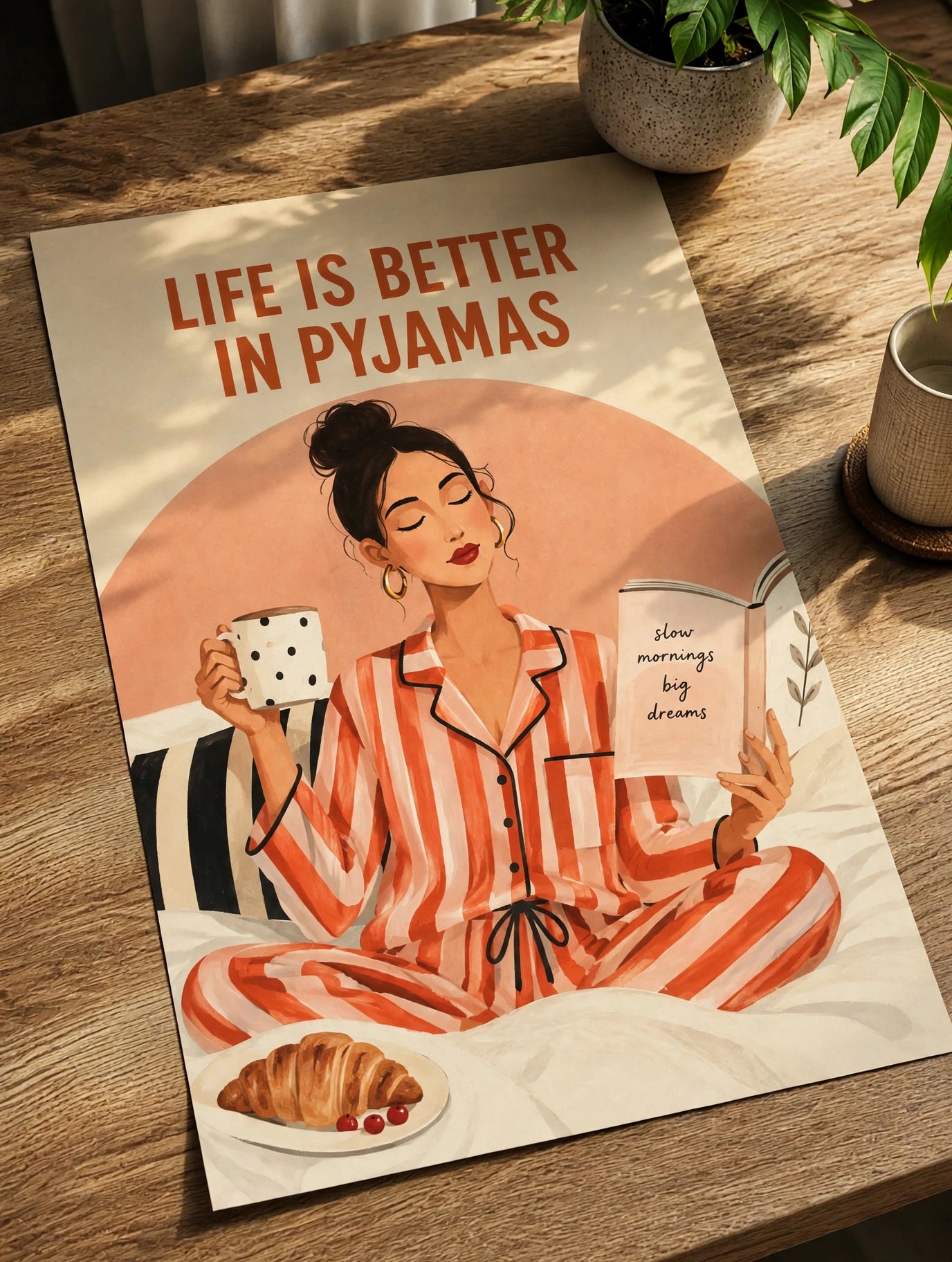 Unframed wall art print on wooden table, woman in striped pajamas and “Life is Better in Pyjamas”