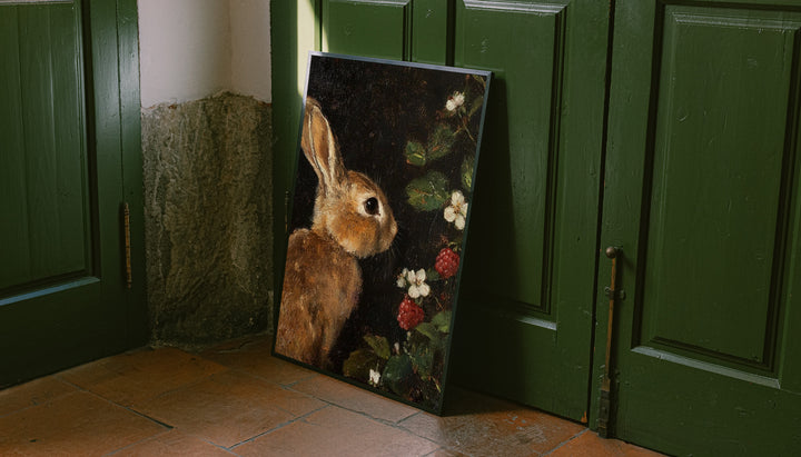 Framed rabbit botanical print leaned against green double doors, vertical wall decor.
