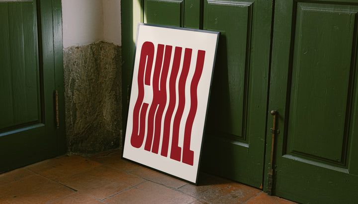 The word CHILL in tall wavy red lettering on a cream background leaning on the floor against dark green wall panelling