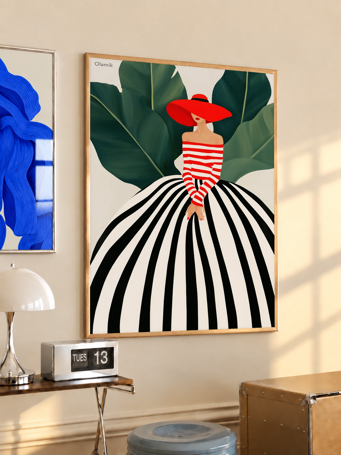 Framed woman portrait art print with red hat, red-and-white stripes, green leaves, light wood frame.