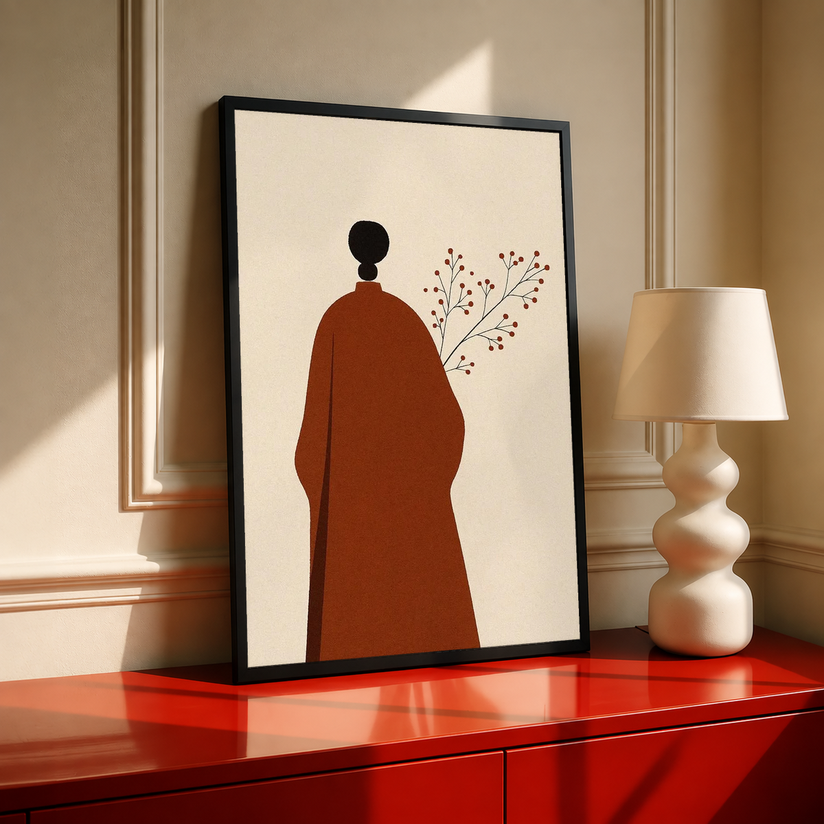 Cream art print with red robed figure silhouette, black head, and delicate branch in black frame