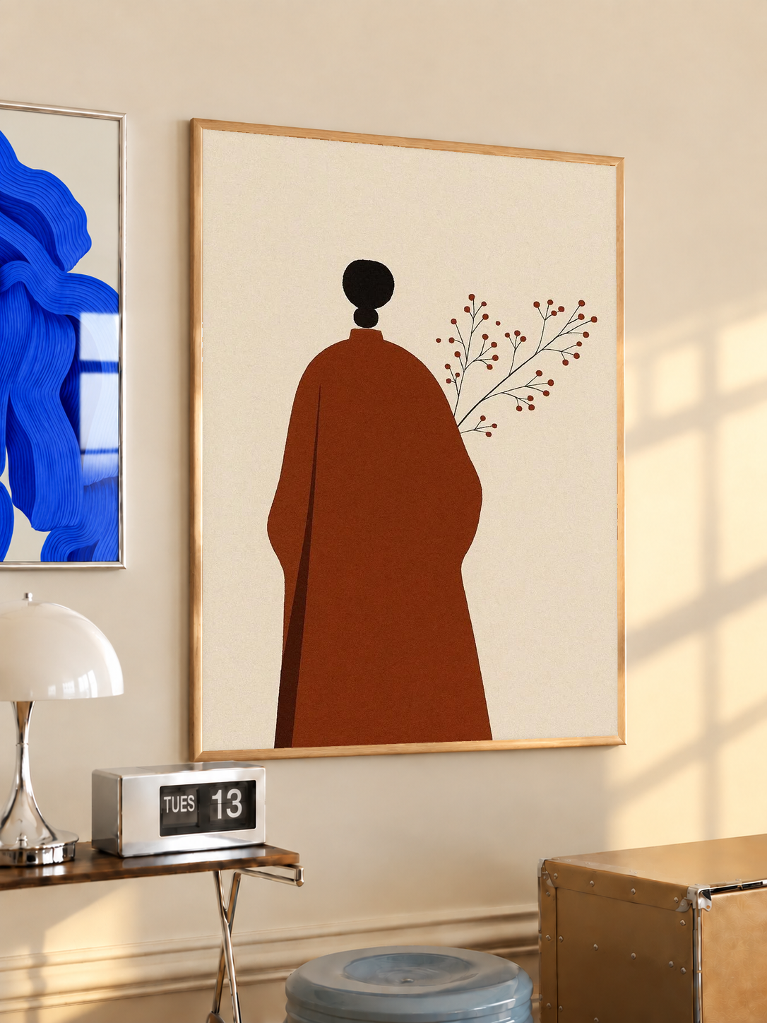 Cream art print with red robed figure silhouette, black head, and delicate branch in wood frame