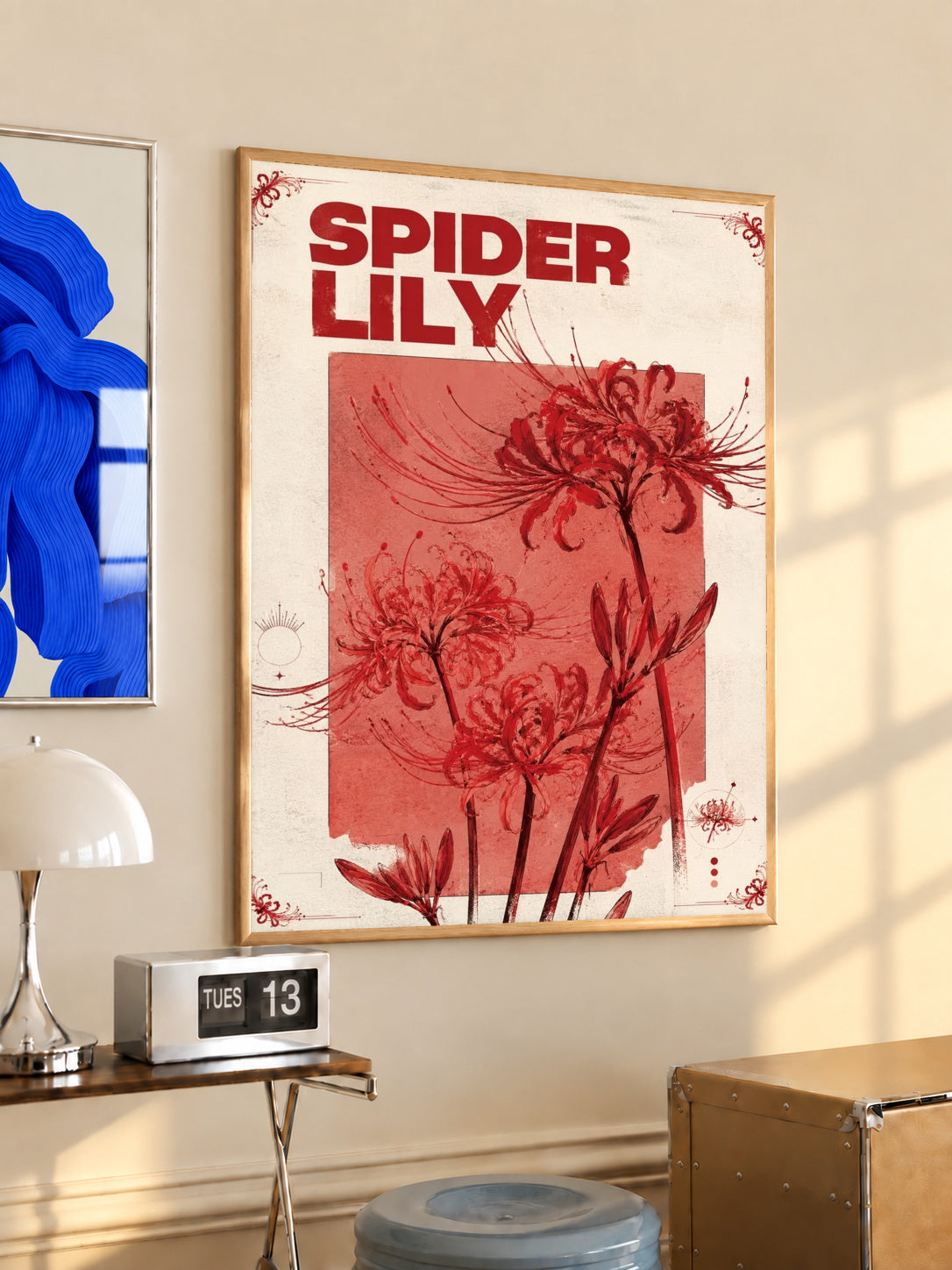 Red spider lily flowers and the words SPIDER LILY in a vintage cream and red botanical design in a light wood frame on a sunlit office wall beside a desk
