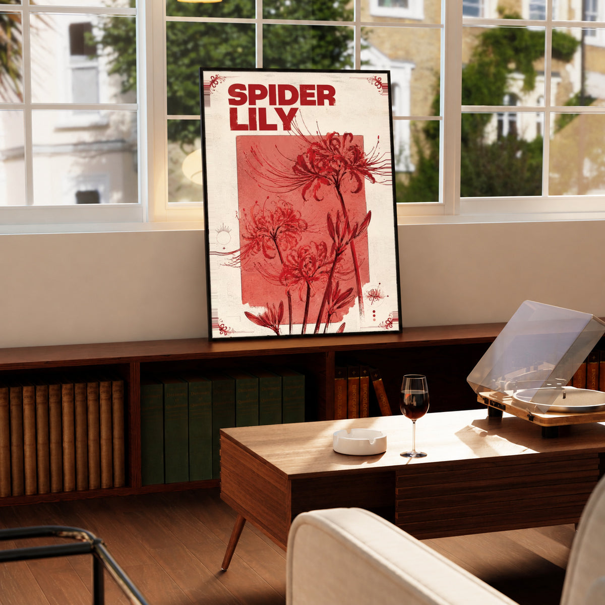 Red spider lily flowers and the words SPIDER LILY in a vintage cream and red botanical design in a black display frame on a wooden console beside a sunlit window