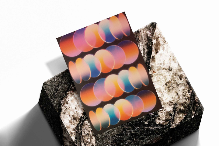 Unframed artwork depicting rows of overlapping graduated oval shapes, presented diagonally on rough stone.