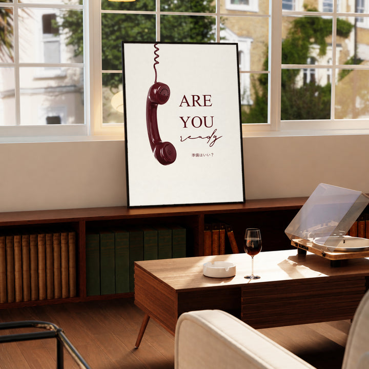 Framed telephone typography poster with burgundy text on cream, standing on tabletop