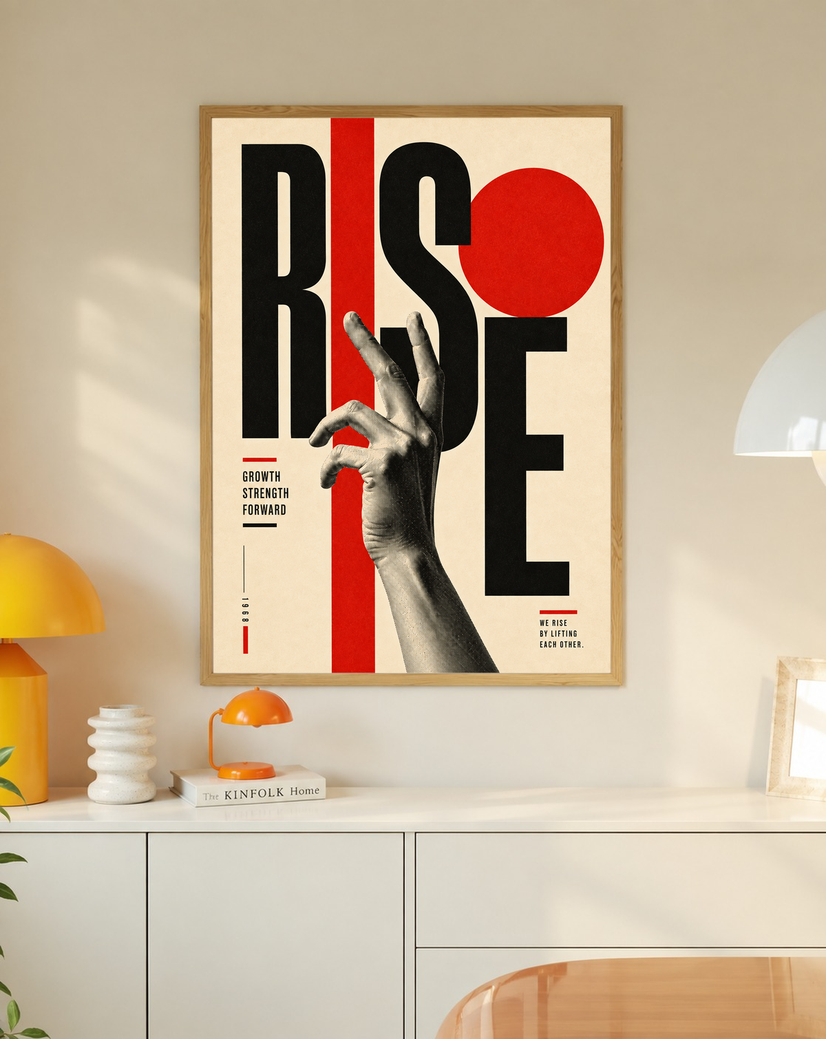 A reaching monochrome hand across oversized Rise lettering and red geometric shapes in a slim oak frame on a cream wall above a white cabinet