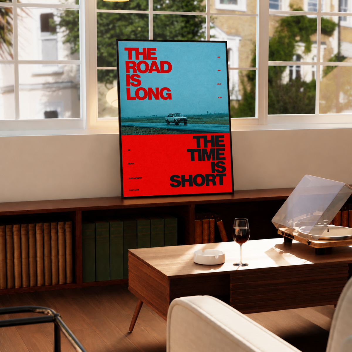 A small vintage car between blue and red blocks with bold road and time lettering in a black frame by a bright window above a record player