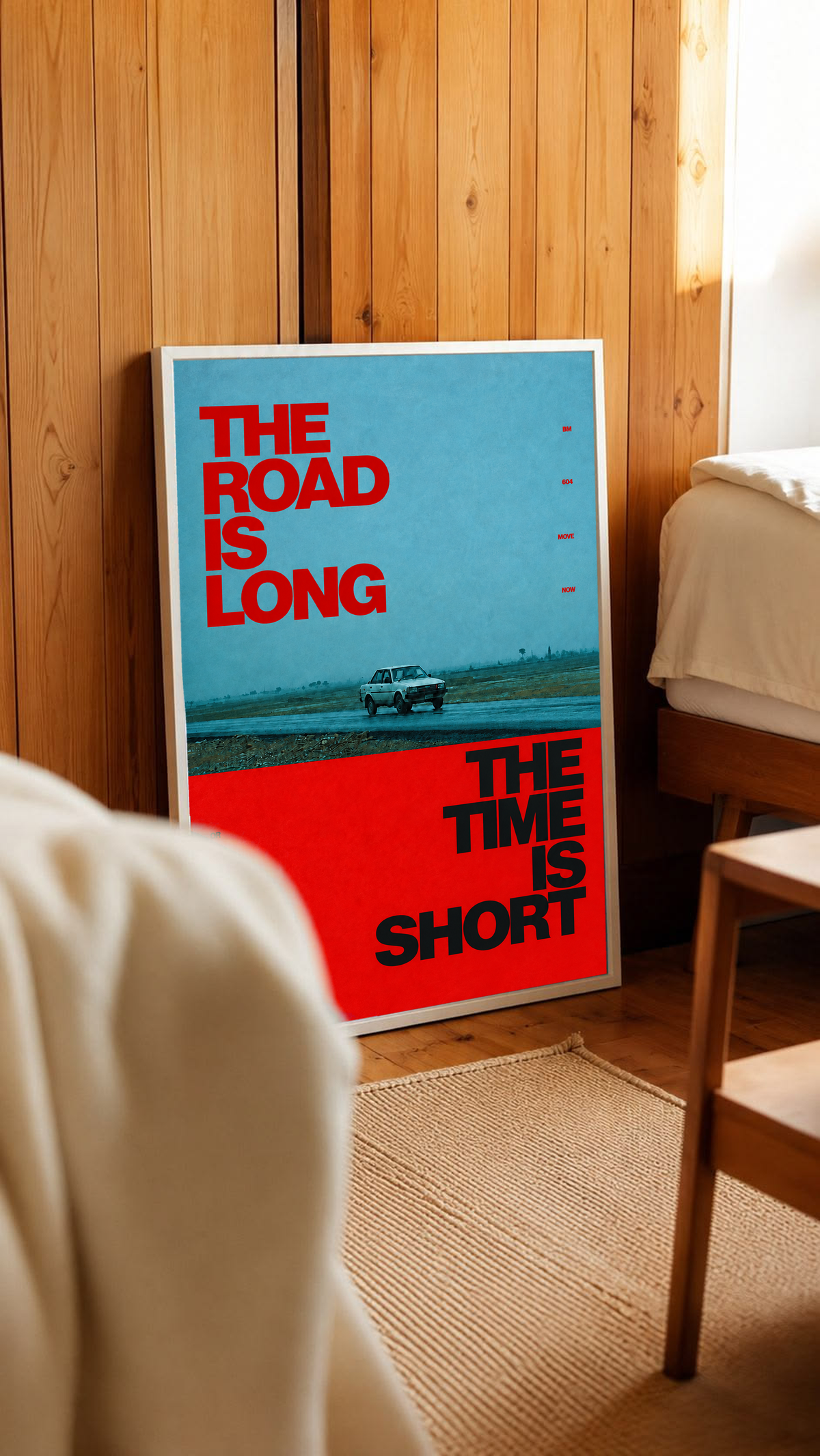 A small vintage car between blue and red blocks with bold road and time lettering in a white frame leaning against warm wooden wall panels