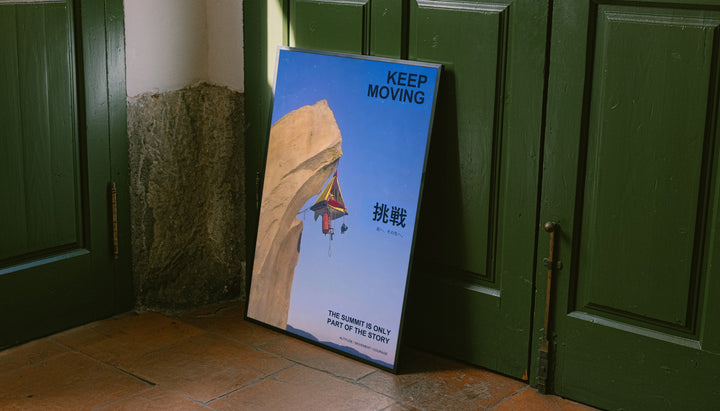 Standing motivational poster in dark frame, blue cliff art with rock climber and "Keep Moving"