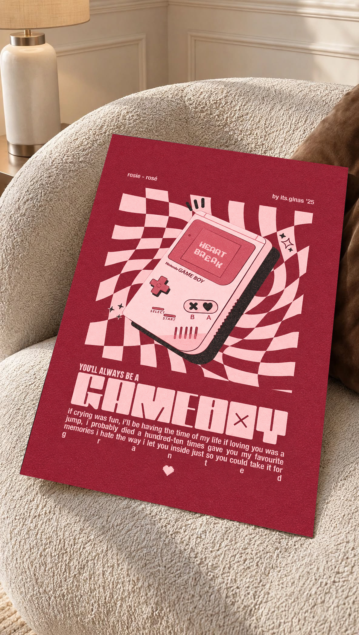 A pink Game Boy-style console with Heart Break screen on a wavy pink checkerboard as an unframed poster resting on a cream woven chair