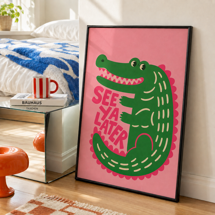 Black-framed wall art with green alligator and 'SEE YA LATER' lettering on pink print