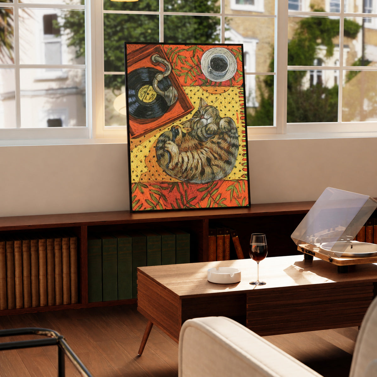 Cat sleeping on vinyl art print in black frame on wooden table by window