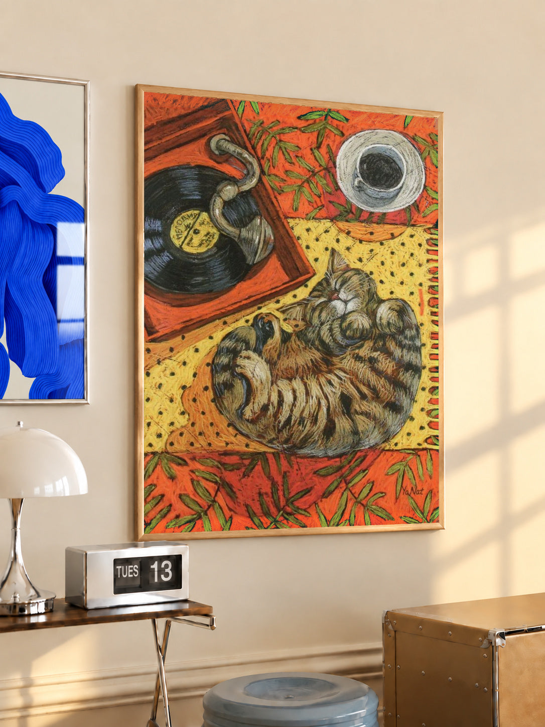 Warm orange cat sleeping on vinyl art print in black frame on cream wall