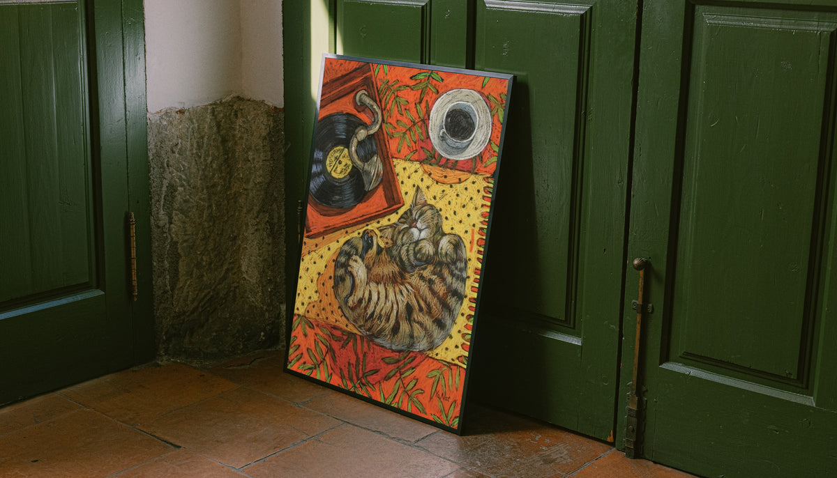 Cat sleeping on vinyl art print in black frame, warm orange collage against dark doors
