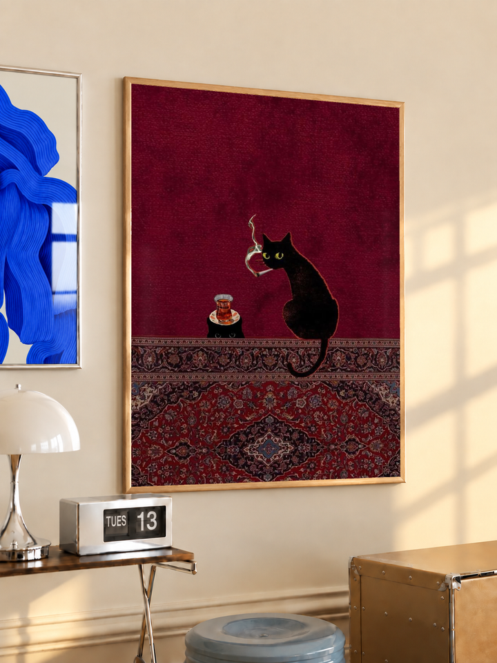 Black cats, tea glass and smoking motif in an oak frame on a warm cream wall above a small table and dome lamp