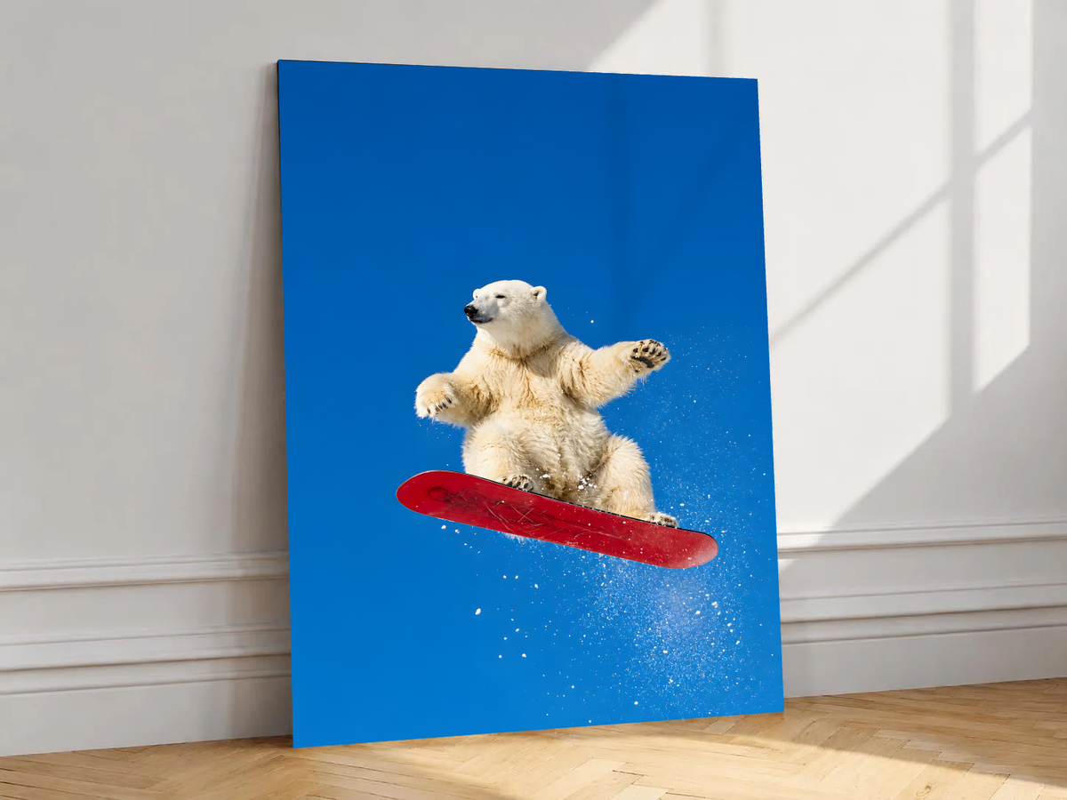 White polar bear airborne on a red snowboard with scattered snow against a bright blue sky, shown unframed on a white wall above parquet flooring with a diagonal sun shadow