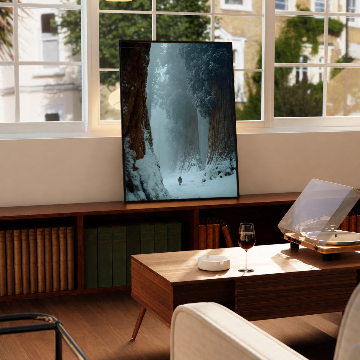 Black-framed winter forest print leaning on a table by large windows