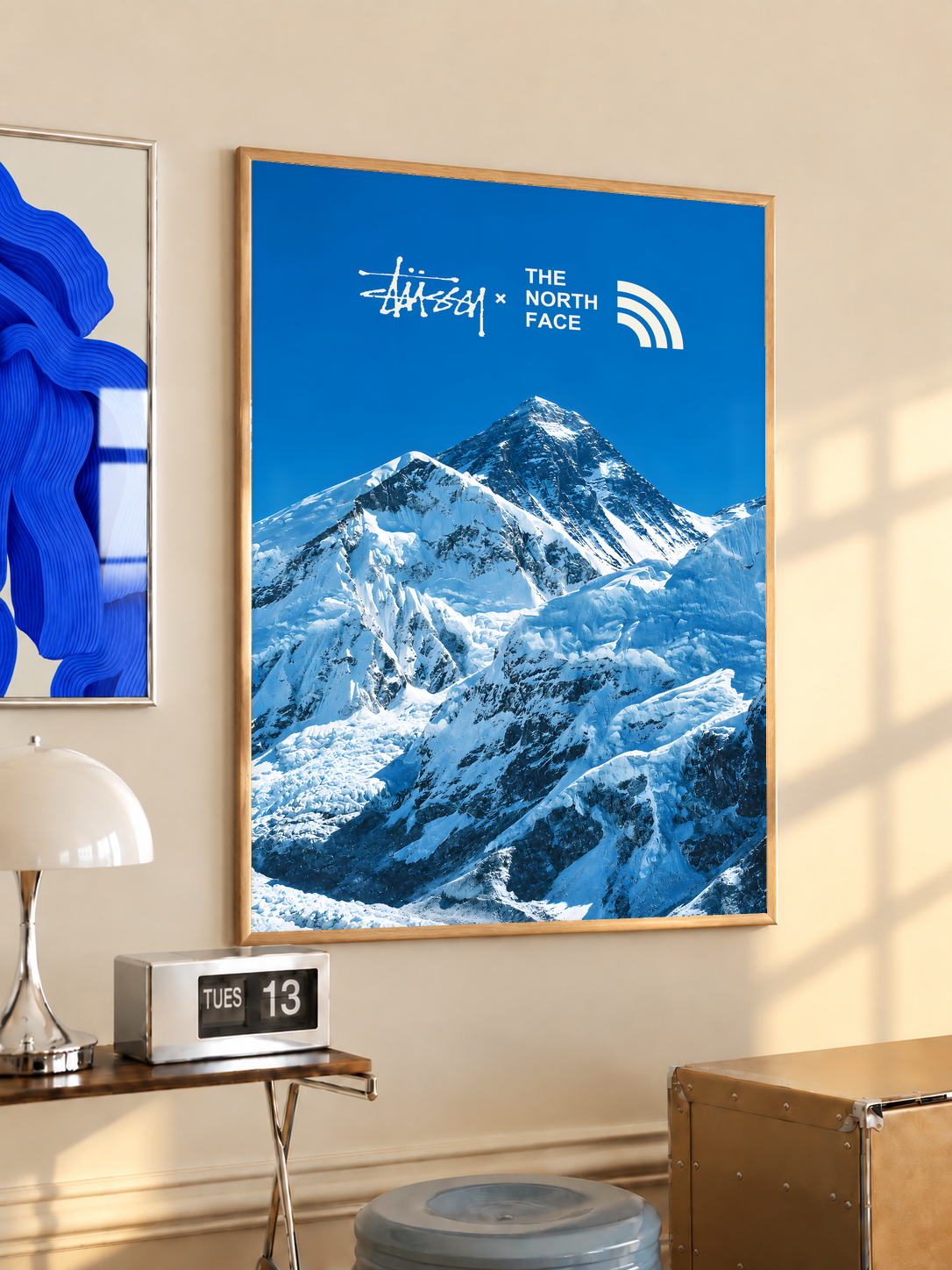 Blue snowy mountain landscape with Stussy and The North Face marks; oak framed print in a desk setting