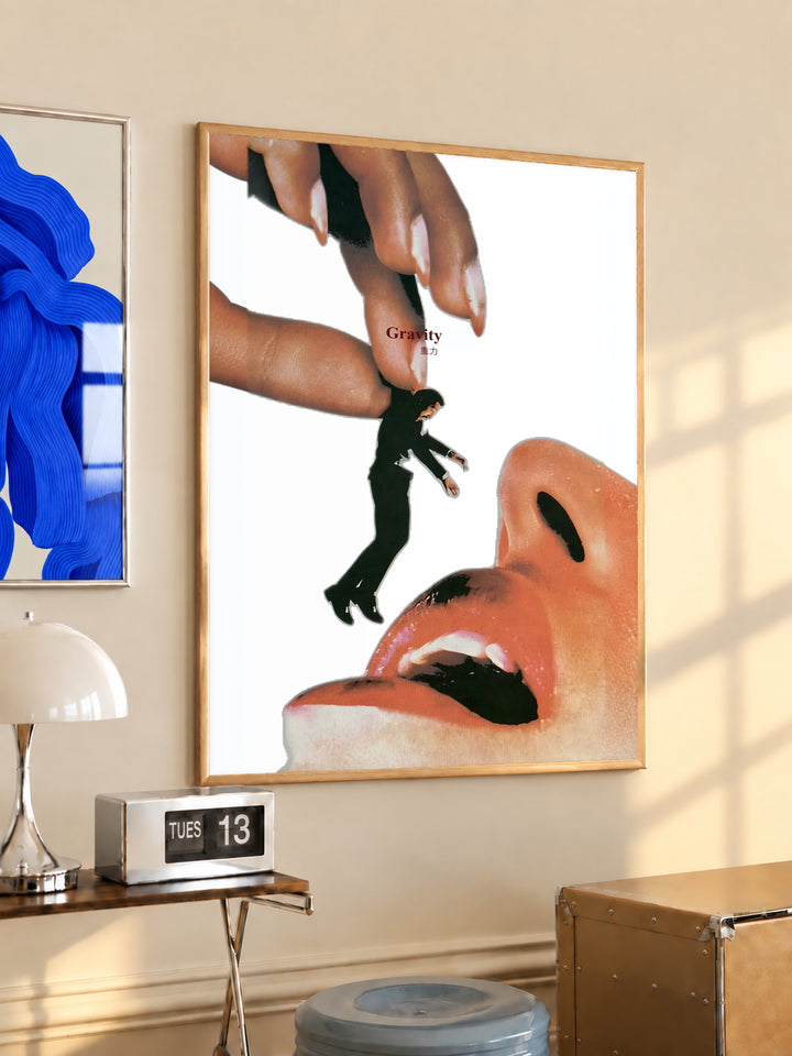 Wood-framed surreal collage poster featuring giant hand, miniature figure, and open mouth