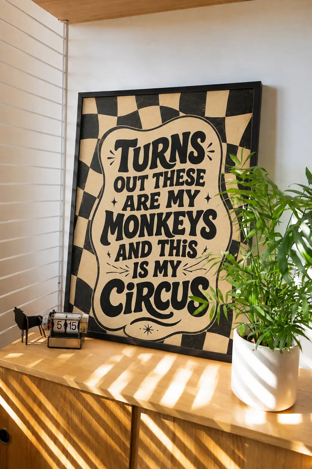 Framed wall art with black frame, checkered border, and bold quote text on beige
