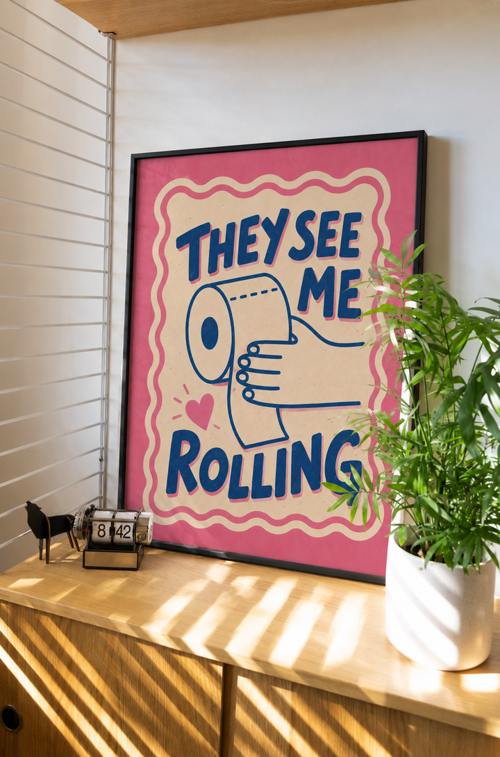 Framed wall art print with pink background and blue “THEY SEE ME ROLLING” text
