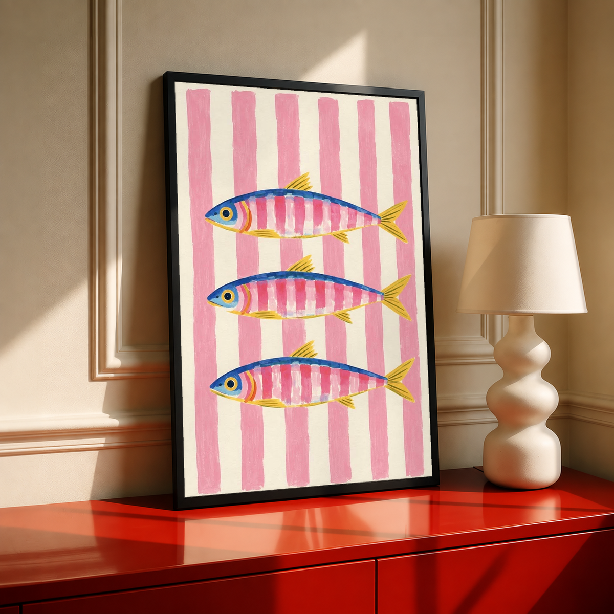 Black-framed art print with three striped fish in blue and yellow on pink bands