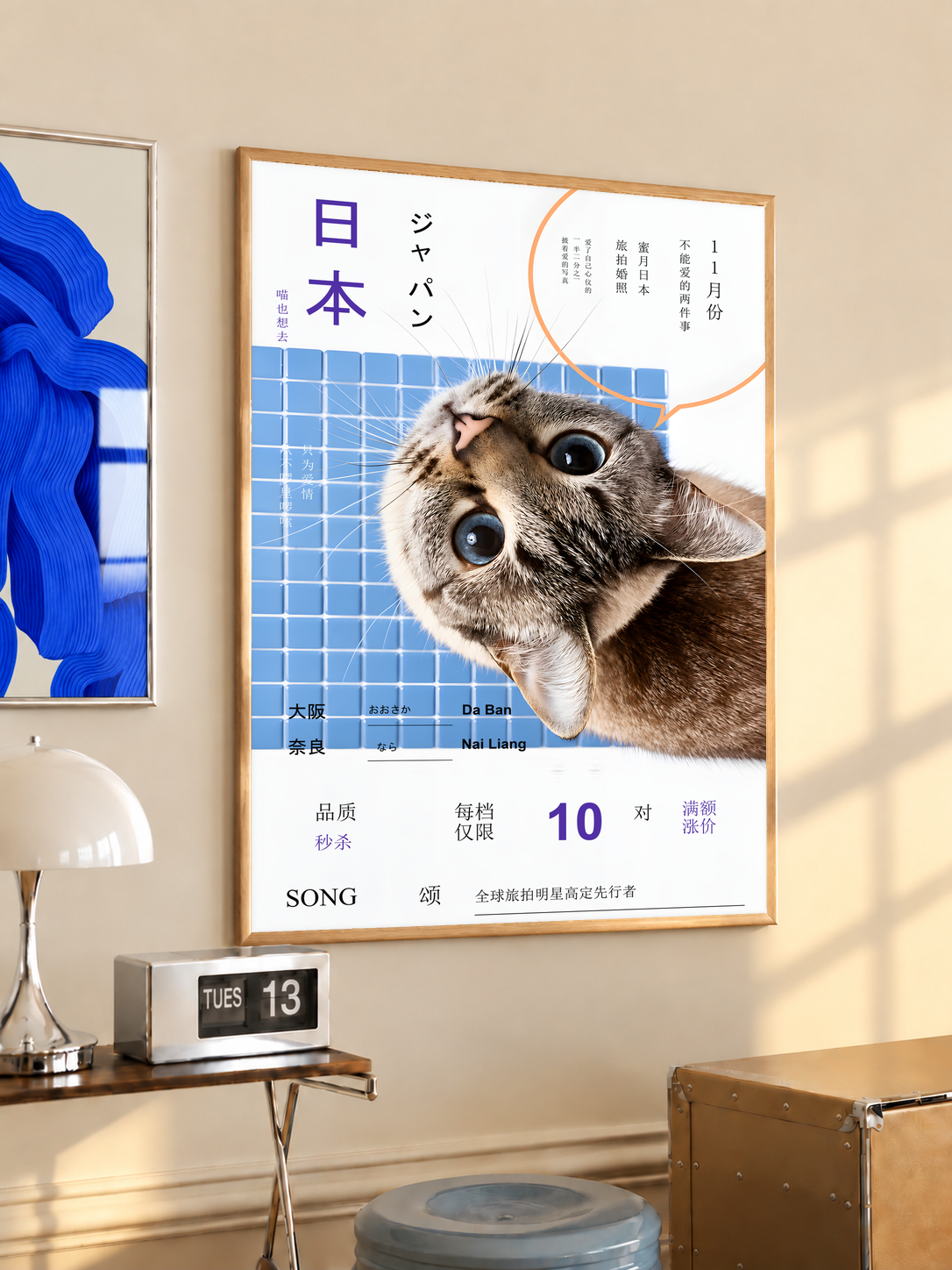 Wide-eyed tilted tabby cat on a blue grid with Japanese lettering; oak framed print in a desk setting